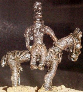 Статуэтка из бронзы. Амазонка на коне в упряжи для верховой езды, в доспехах и с длинной косой (косами), в маске и со шлемом на голове, но без оружия.